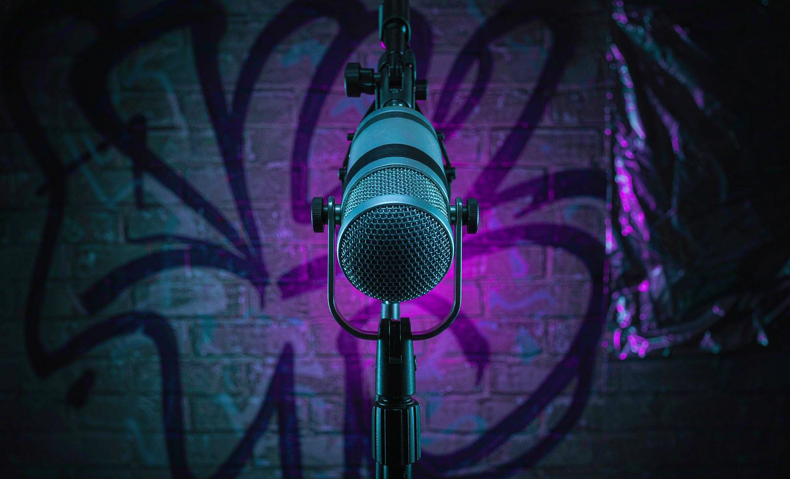 Studio microphone glowing under neon light in front of a graffiti wall, representing the rap lyrics generator collection